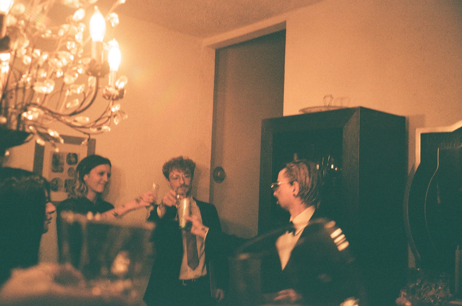 Players in costume toast under a lit chandelier in the castle's main room.