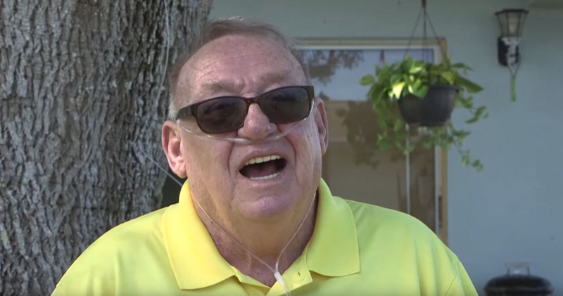 Still from Sunset Eddy: an older man in sunglasses and a yellow shirt, laughing on his porch.